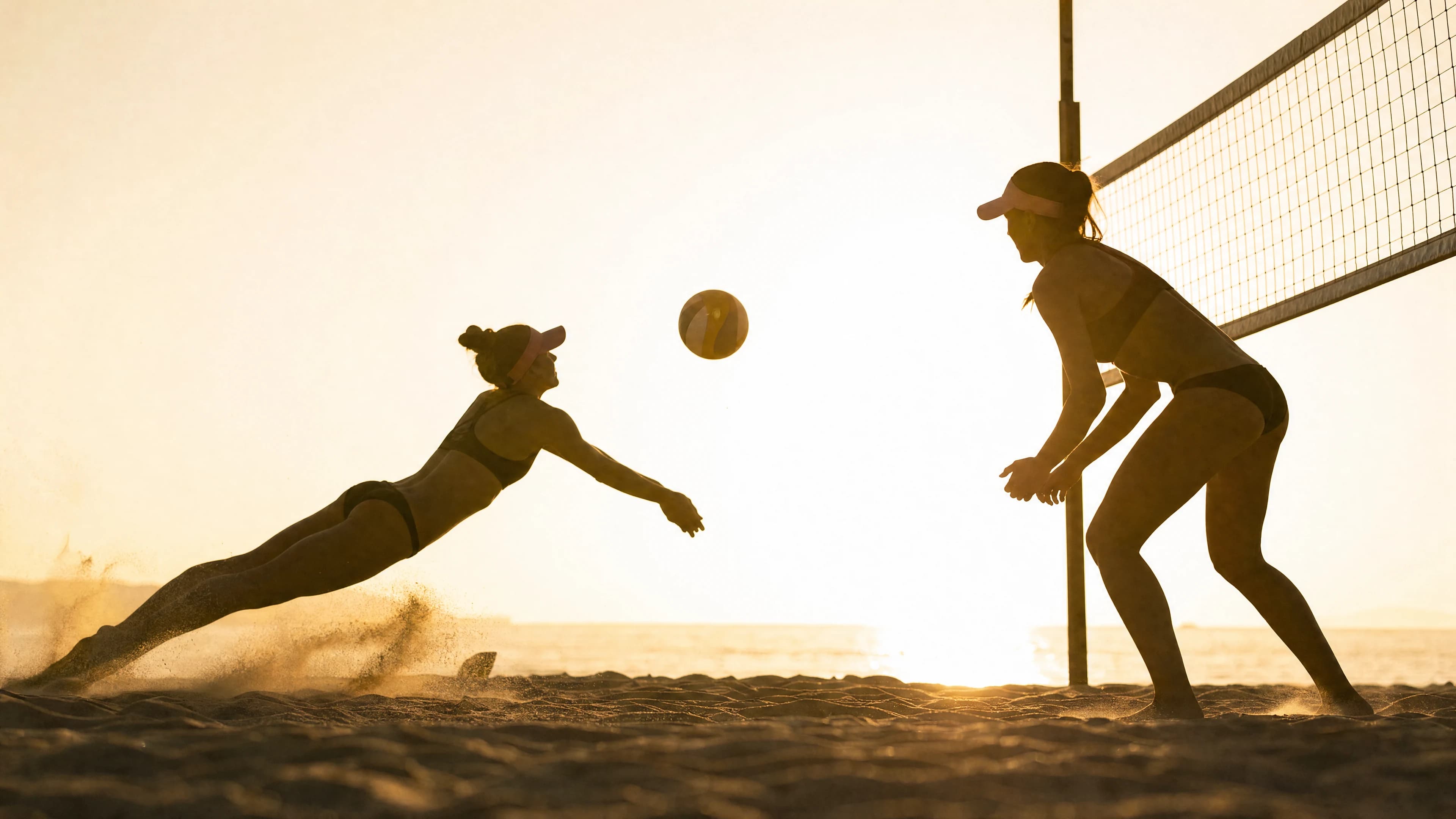 Two anonymous beach volleyball players moving through a backlit rally