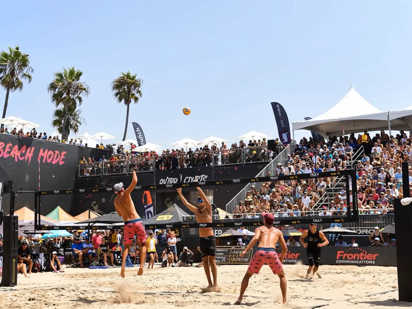 Beach volleyball players competing on a packed center court